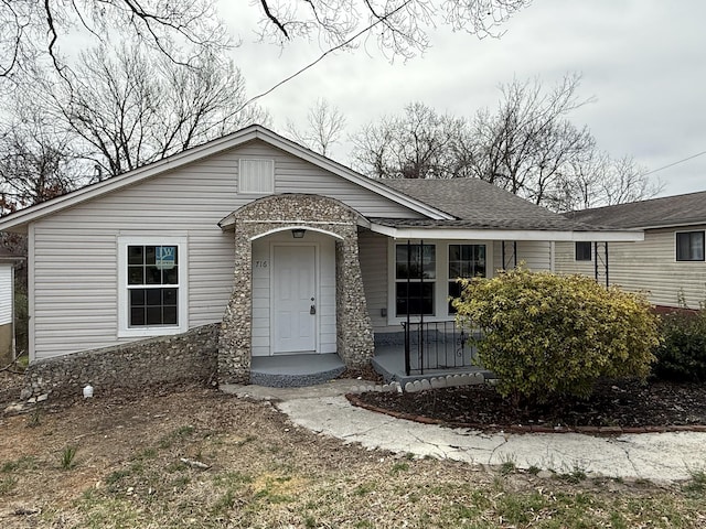 ranch-style home with a porch and roof with shingles