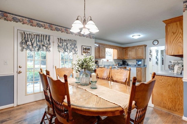 dining area with a textured ceiling, hardwood / wood-style flooring, and a notable chandelier