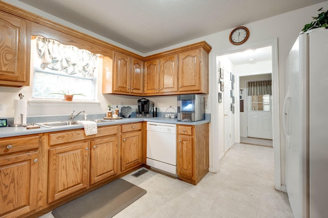 kitchen featuring a textured ceiling, sink, and white appliances