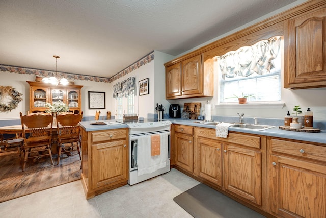 kitchen featuring sink, kitchen peninsula, decorative light fixtures, white range with electric cooktop, and a chandelier