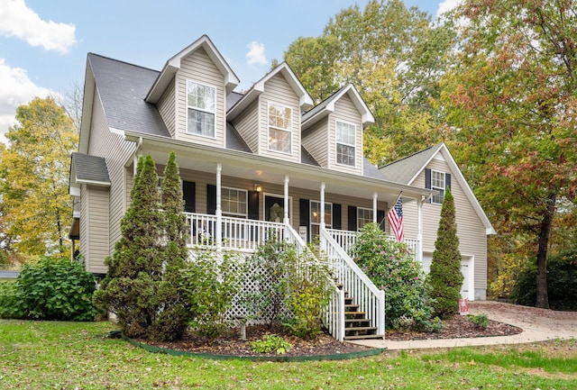 cape cod-style house featuring a front lawn, a garage, and covered porch