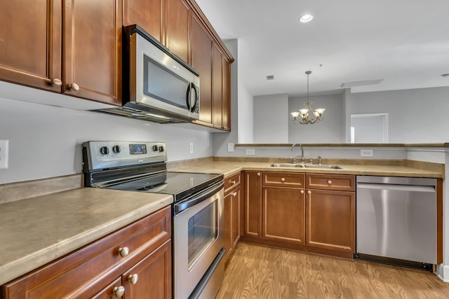 kitchen with stainless steel appliances, light hardwood / wood-style floors, a chandelier, sink, and decorative light fixtures