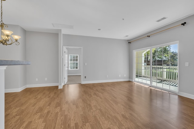 unfurnished living room with an inviting chandelier and light wood-type flooring