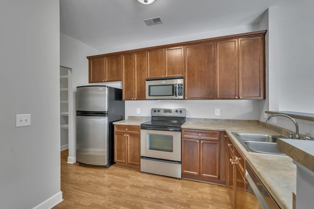 kitchen with stainless steel appliances, sink, and light hardwood / wood-style flooring