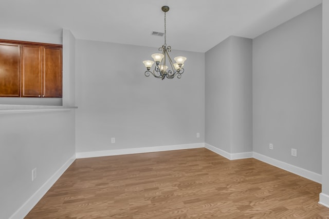 empty room with light hardwood / wood-style flooring and a notable chandelier