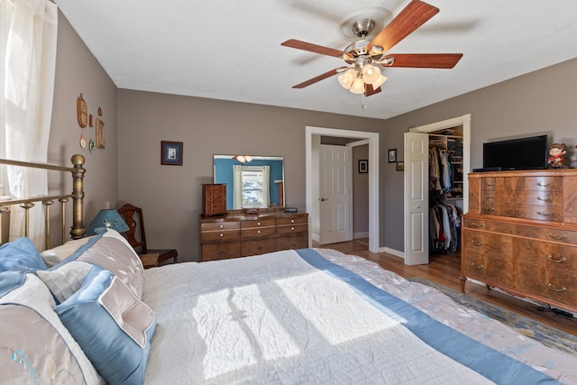 bedroom with wood-type flooring, a closet, a spacious closet, and ceiling fan