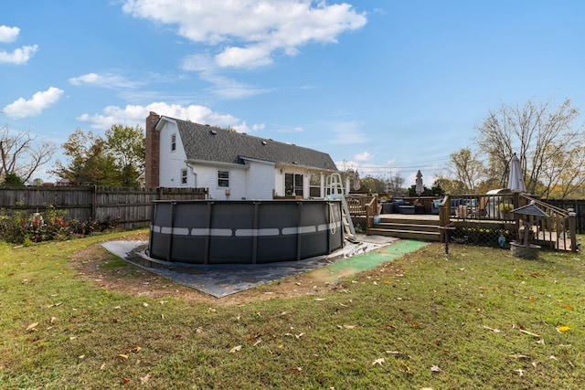 rear view of house with a yard and a pool side deck