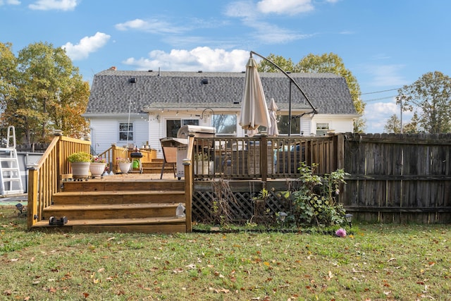 rear view of property featuring a lawn and a wooden deck