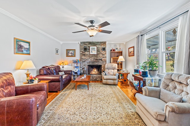 living room with ceiling fan, wood-type flooring, ornamental molding, and a brick fireplace