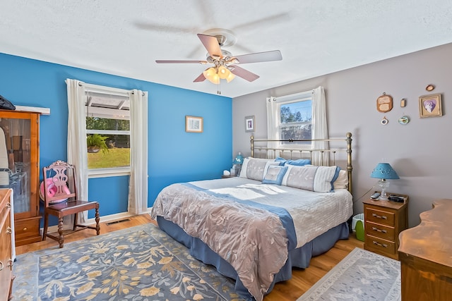 bedroom featuring ceiling fan, light wood-type flooring, and a textured ceiling