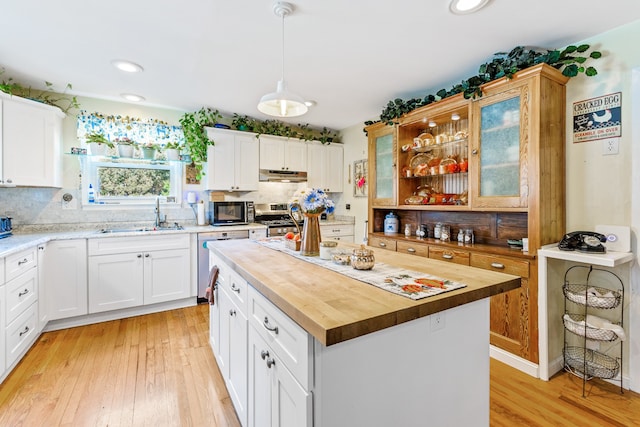 kitchen featuring sink, a center island, wood counters, white cabinets, and appliances with stainless steel finishes