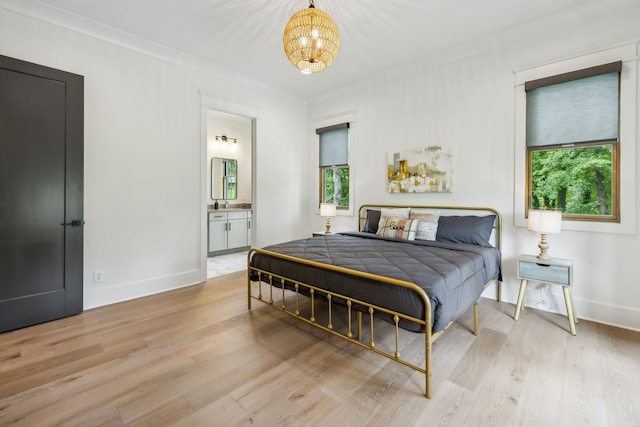 bedroom with light wood-type flooring, multiple windows, ornamental molding, and ensuite bath