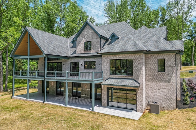 rear view of house with central AC unit, a yard, and a patio