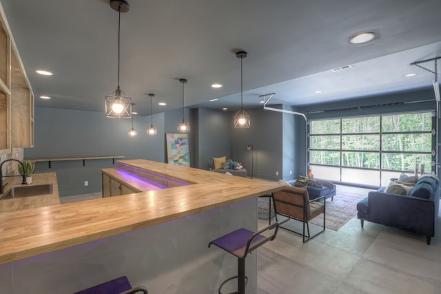 kitchen featuring kitchen peninsula, sink, decorative light fixtures, and wood counters