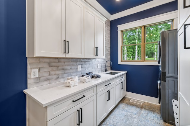 kitchen featuring tasteful backsplash, sink, stainless steel fridge, and white cabinets