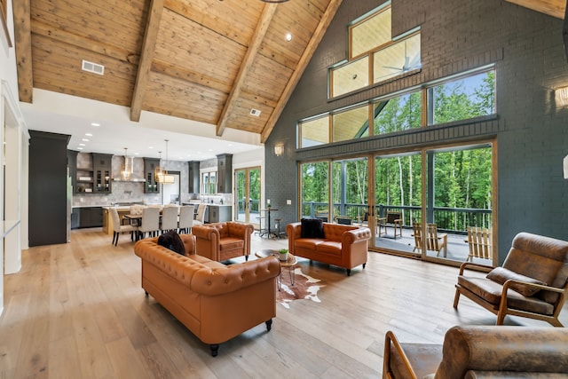 living room with beamed ceiling, plenty of natural light, light wood-type flooring, and high vaulted ceiling