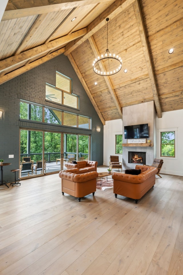 living room with a wealth of natural light, a notable chandelier, high vaulted ceiling, beamed ceiling, and light wood-type flooring