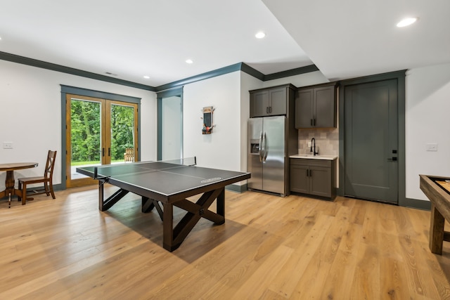 game room with sink, light hardwood / wood-style floors, and crown molding