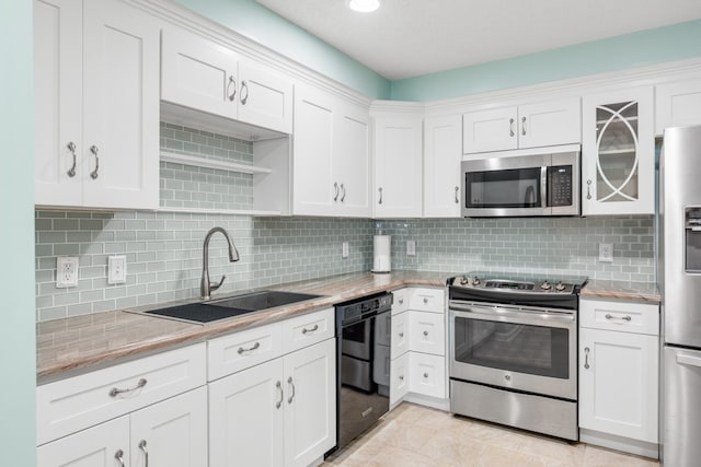 kitchen featuring decorative backsplash, white cabinetry, appliances with stainless steel finishes, and sink