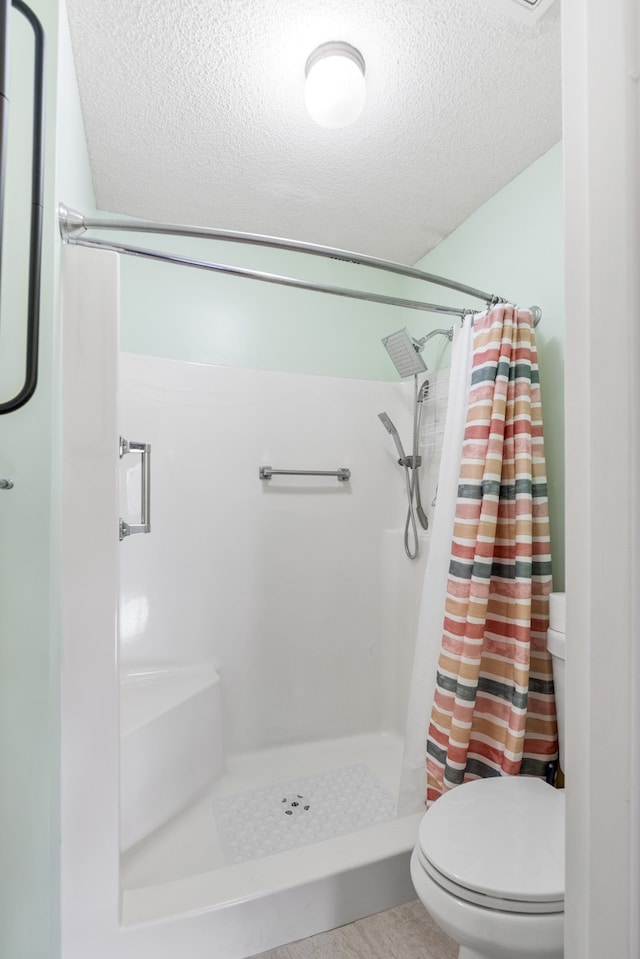 bathroom featuring toilet, a textured ceiling, and a shower with shower curtain