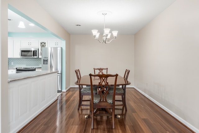 dining space with dark wood-type flooring and an inviting chandelier