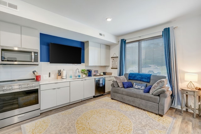 kitchen featuring stainless steel appliances, white cabinets, and light wood-type flooring