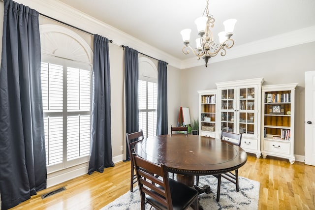 dining area featuring light wood-type flooring, crown molding, and an inviting chandelier