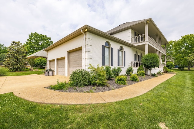 view of side of home with a garage, a lawn, and a balcony