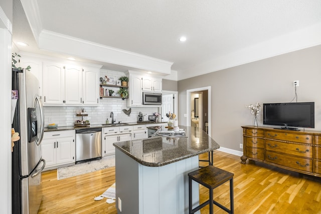 kitchen with white cabinets, a kitchen breakfast bar, light hardwood / wood-style flooring, and appliances with stainless steel finishes