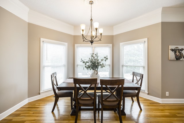 dining room featuring a textured ceiling, wood-type flooring, a notable chandelier, and crown molding