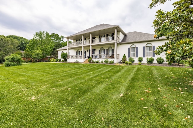 rear view of house with a lawn and a balcony