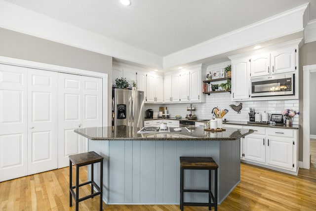 kitchen featuring stainless steel appliances, light hardwood / wood-style floors, a breakfast bar area, a kitchen island, and white cabinets