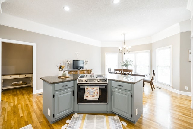 kitchen featuring an inviting chandelier, a textured ceiling, stainless steel range with electric cooktop, light hardwood / wood-style flooring, and decorative light fixtures