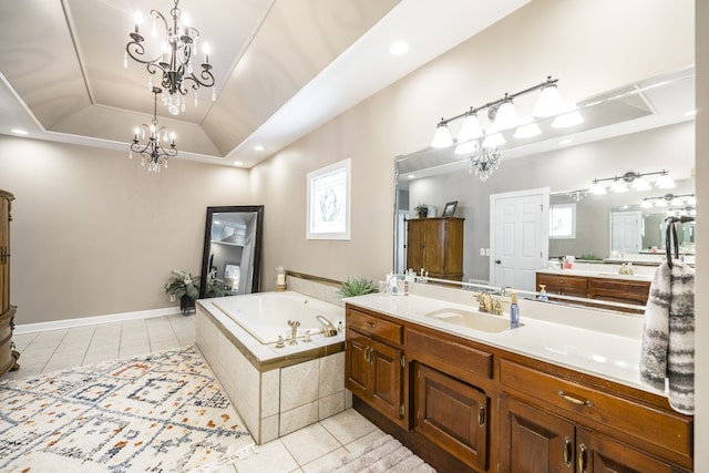 bathroom with tiled tub, a tray ceiling, vanity, a notable chandelier, and tile patterned floors