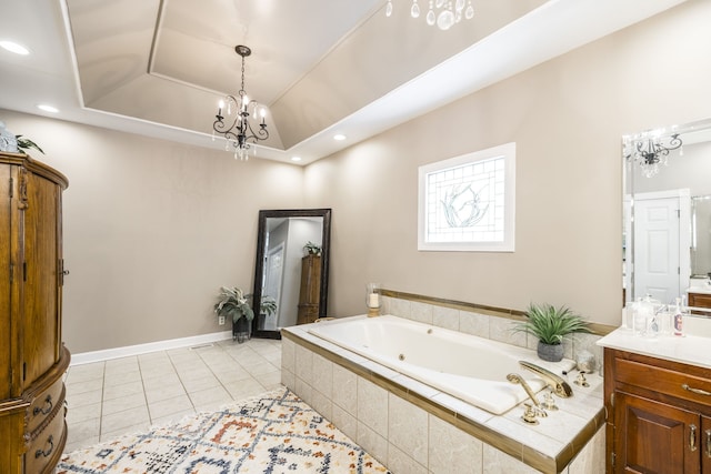 bathroom with tiled tub, vanity, tile patterned flooring, a tray ceiling, and a chandelier