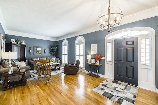 foyer with light hardwood / wood-style flooring, a notable chandelier, and crown molding