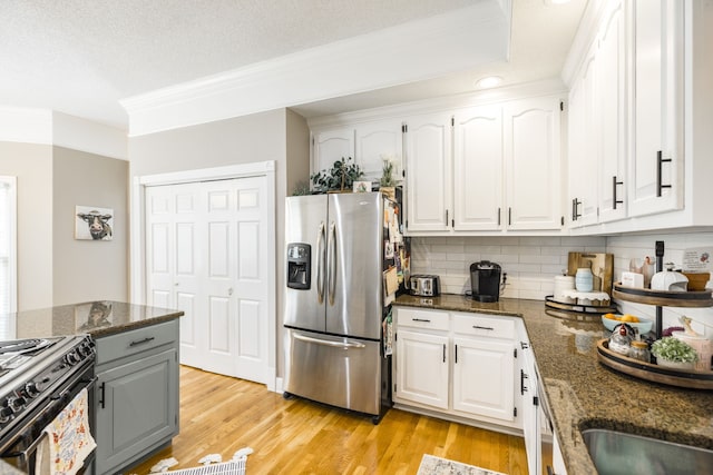 kitchen featuring light hardwood / wood-style floors, stainless steel fridge, white cabinetry, and dark stone countertops