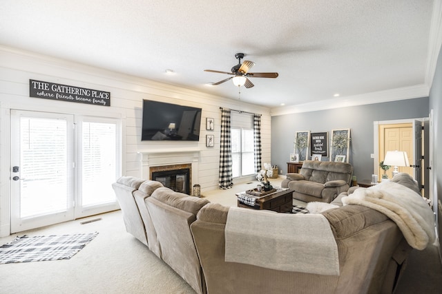 carpeted living room with a textured ceiling, a wealth of natural light, wooden walls, and ceiling fan