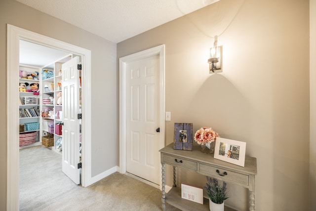 corridor with a textured ceiling and light carpet