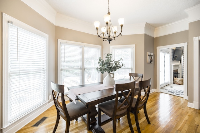 dining room featuring a chandelier, light wood-type flooring, and crown molding