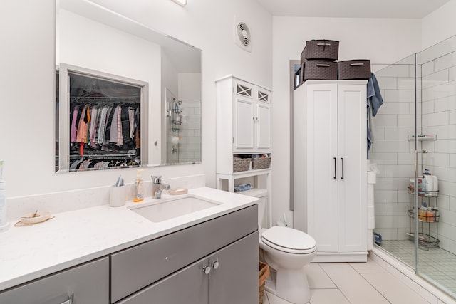 bathroom featuring tile patterned flooring, vanity, toilet, and a shower with door