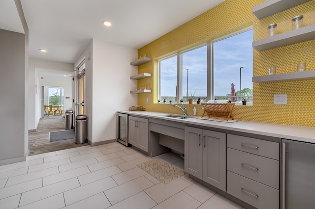 kitchen featuring wine cooler, backsplash, sink, and gray cabinets