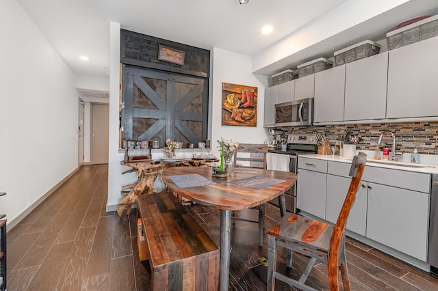 dining room with a barn door, sink, and dark wood-type flooring