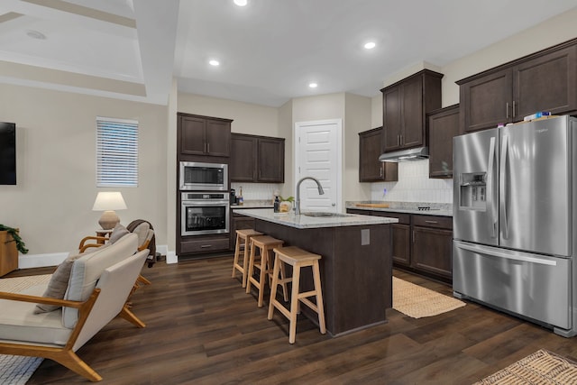 kitchen with a kitchen island with sink, sink, dark wood-type flooring, and appliances with stainless steel finishes