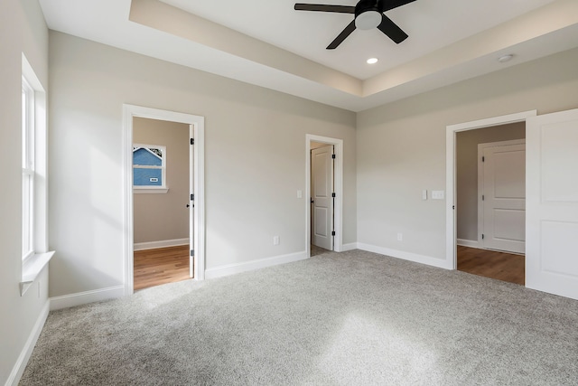 unfurnished bedroom with carpet, ceiling fan, a raised ceiling, and connected bathroom