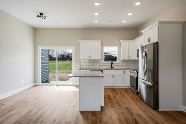 kitchen with a kitchen island, light wood-type flooring, white cabinets, and stainless steel appliances