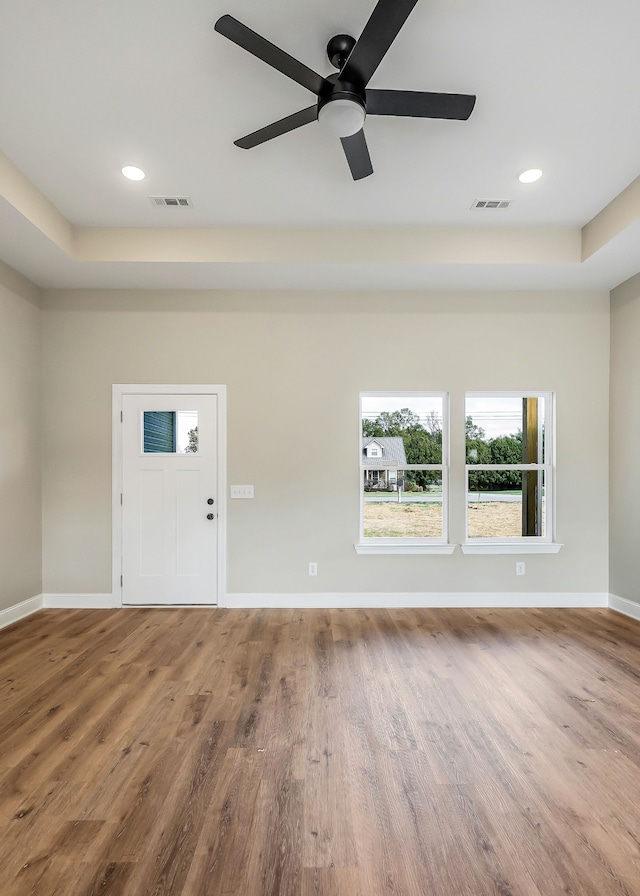 foyer entrance with ceiling fan, wood-type flooring, and a raised ceiling