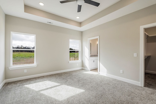 unfurnished bedroom with a closet, a spacious closet, carpet floors, ceiling fan, and ensuite bathroom