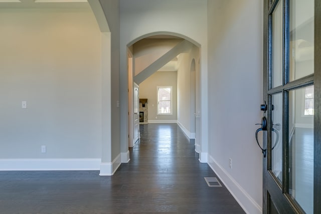 foyer entrance with a brick fireplace and dark wood-type flooring