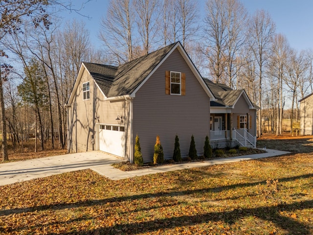 view of side of property with a yard, covered porch, and a garage